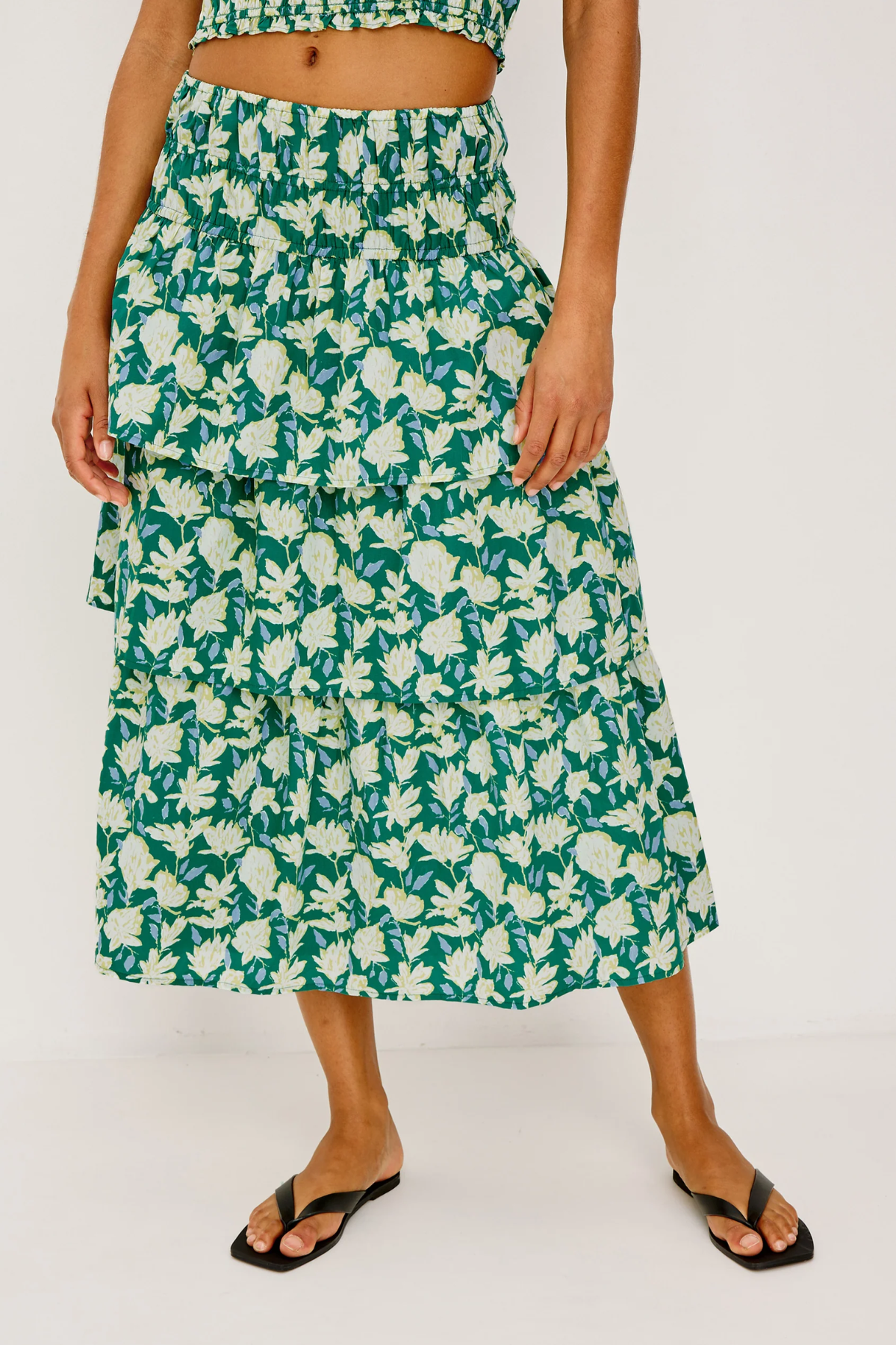 Person wearing a green floral skirt on a white background