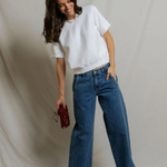 woman in white short sleeve top and blue denim on draped background 