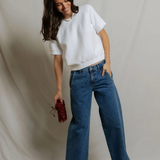 woman in white short sleeve top and blue denim on draped background 