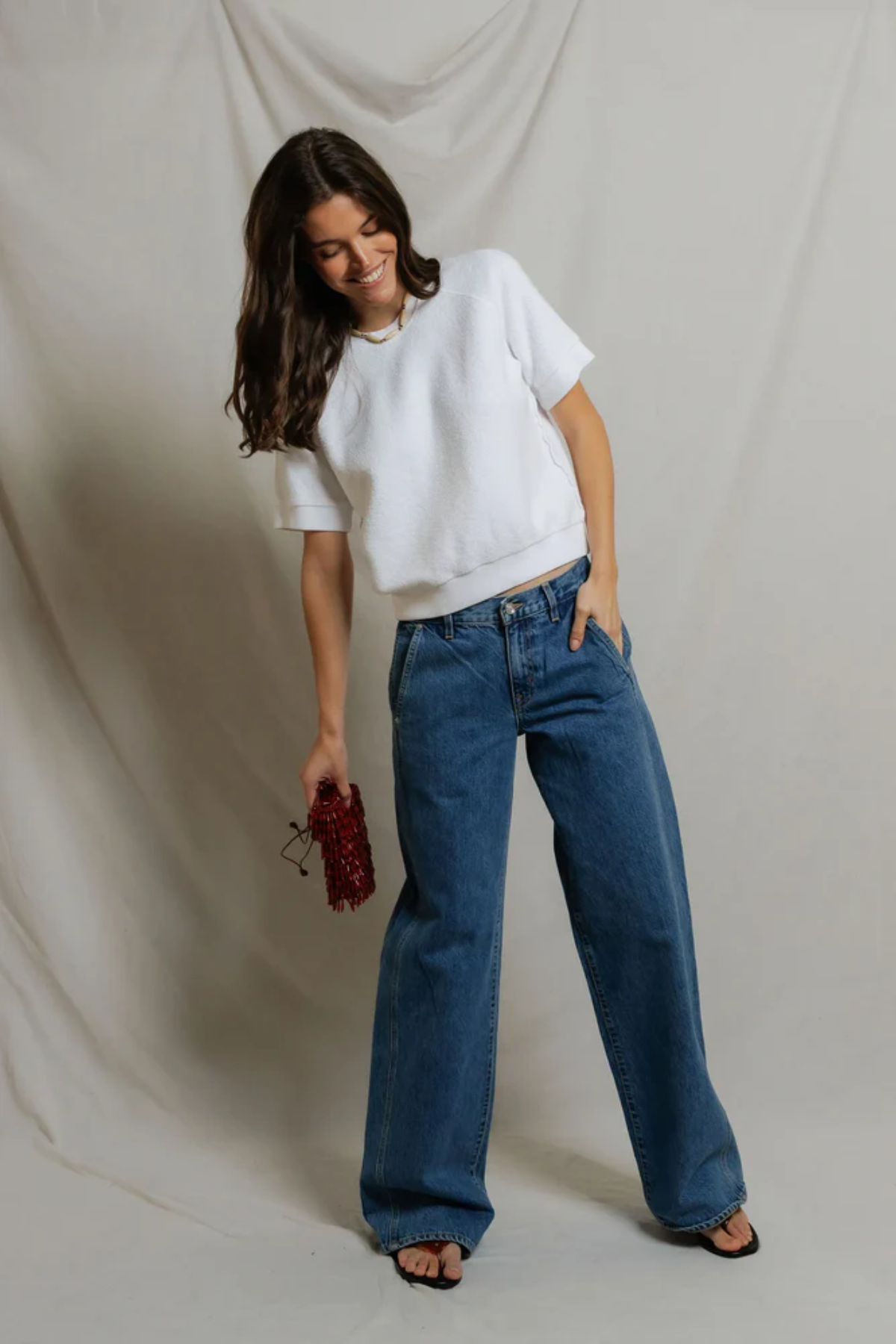 woman in white short sleeve top and blue denim on draped background 