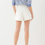 Person wearing a blue and white striped shirt and white shorts on a plain background