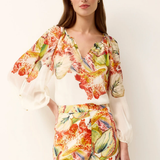 woman in printed blouse and shorts on white background 