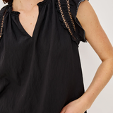 Black sleeveless top with ruffled shoulders on a white background