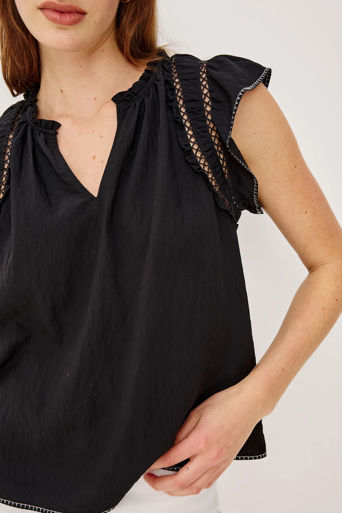 Black sleeveless top with ruffled shoulders on a white background