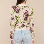 Person wearing a floral cardigan with a beige background