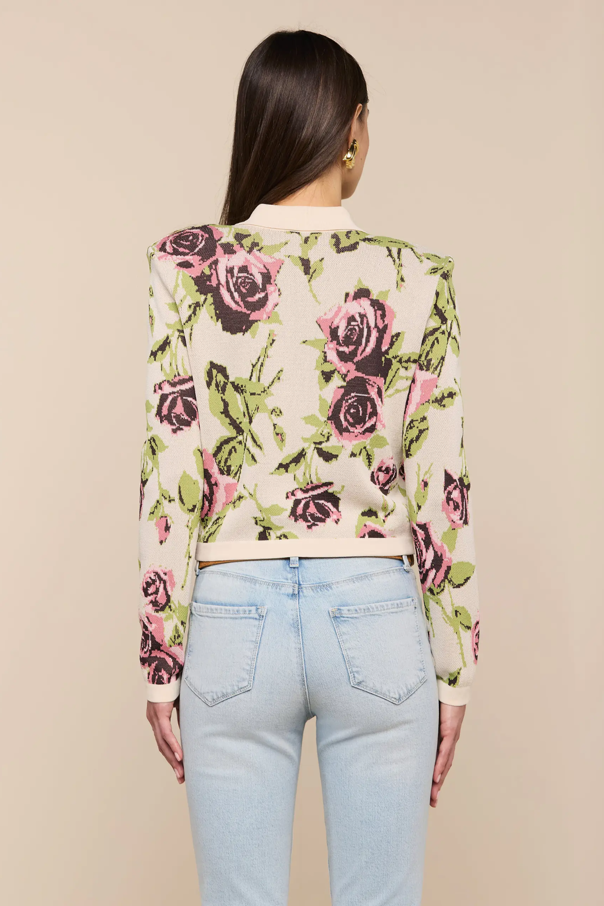 Person wearing a floral cardigan with a beige background