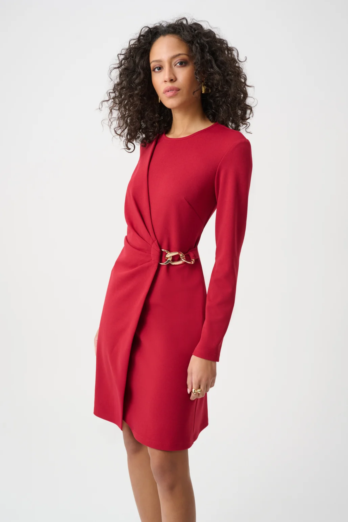 Woman wearing a red dress with a gold belt on a white background