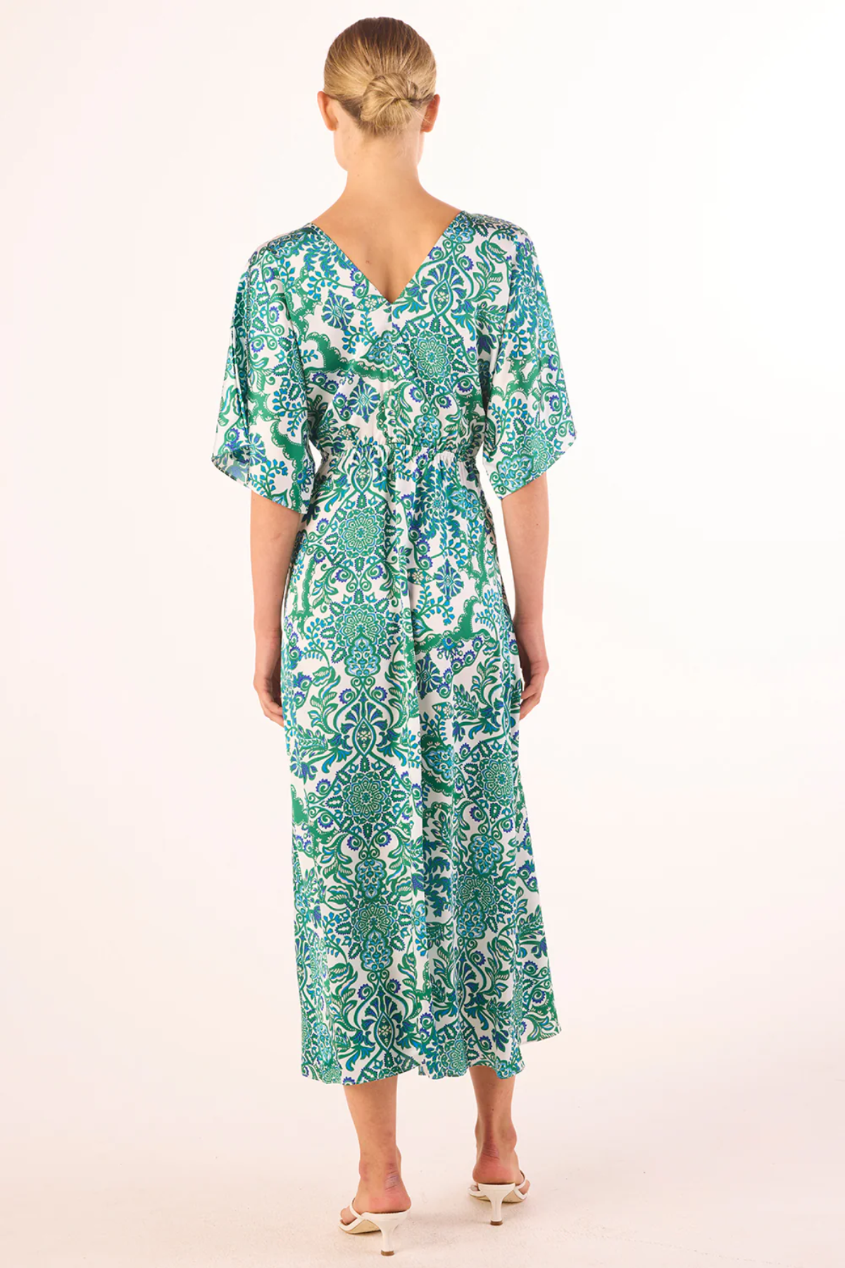 Woman wearing a green patterned dress on a white background