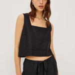 Woman wearing a black sleeveless top and black pants on a white background