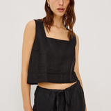 Woman wearing a black sleeveless top and black pants on a white background