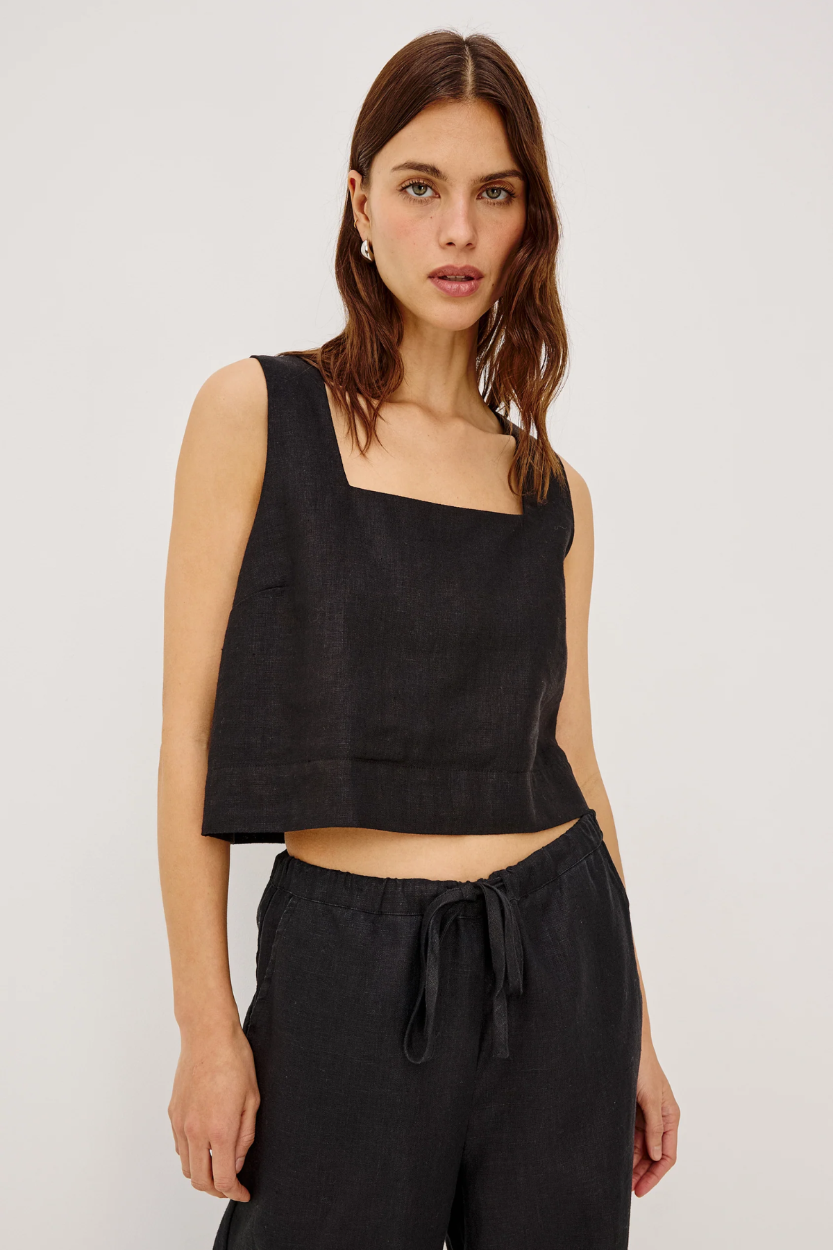 Woman wearing a black sleeveless top and black pants on a white background