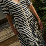Person wearing a black and white striped dress on a wooden deck.