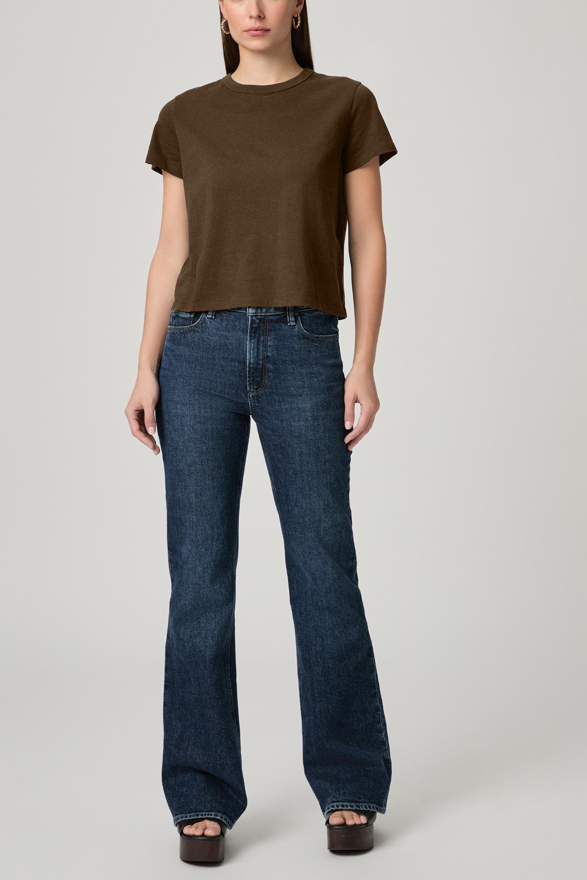Person wearing a brown t-shirt and blue jeans on a plain background