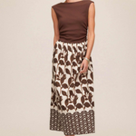 Woman wearing a brown top and patterned skirt on a beige background