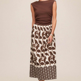 Woman wearing a brown top and patterned skirt on a beige background