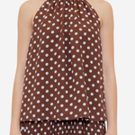 A model wearing a brown halter-neck top and matching pleated skirt set, both featuring a white polka dot pattern, against a plain light gray background.