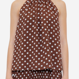 A model wearing a brown halter-neck top and matching pleated skirt set, both featuring a white polka dot pattern, against a plain light gray background.