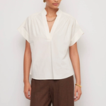Woman wearing a white blouse and brown pants on a plain background