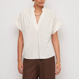 Woman wearing a white blouse and brown pants on a plain background