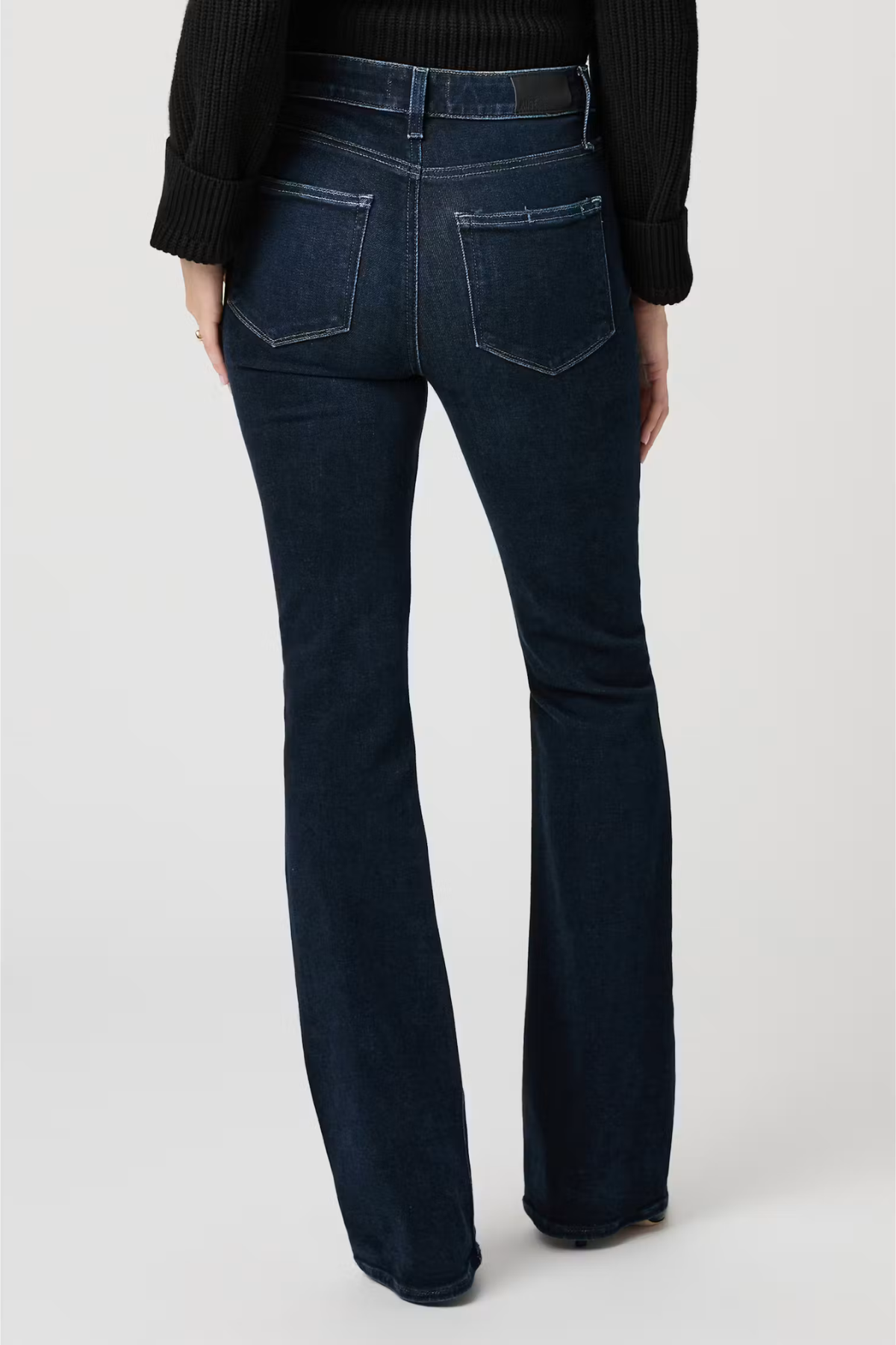 Dark blue jeans worn by a person on a white background