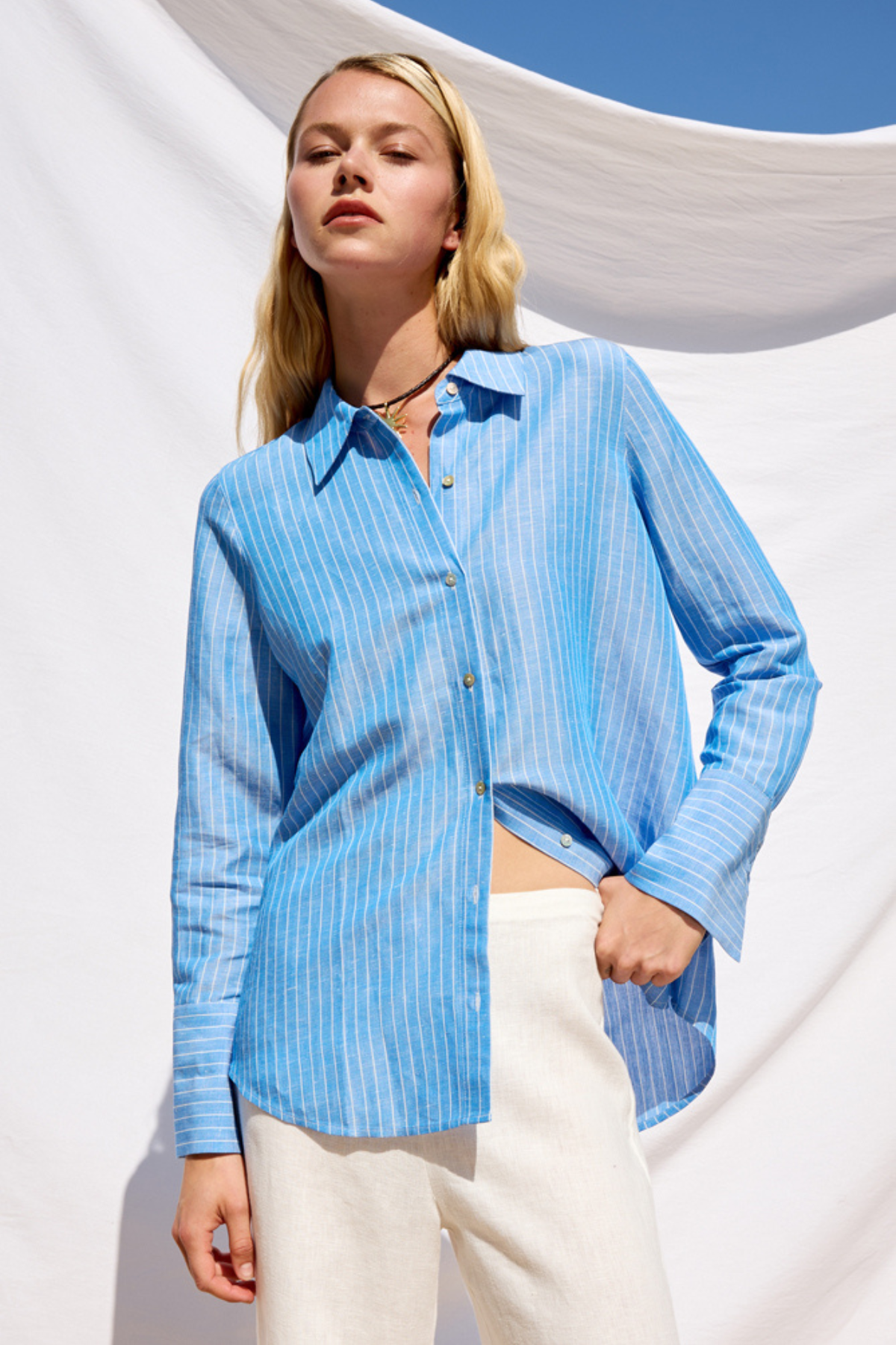 Woman wearing a blue striped shirt against a white background