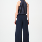A woman shown from the back wearing a sleeveless navy top and matching wide-leg navy pants against a plain light gray studio background.