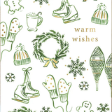 A white holiday greeting card with green line drawings of snowflakes, wreaths, ice skates, mittens, snow boots, gingerbread cookies, and pine branches, with the words 'warm wishes' in gold. A brown kraft envelope is partially visible underneath.