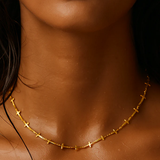 Close-up of a person wearing a gold necklace with a blurred background