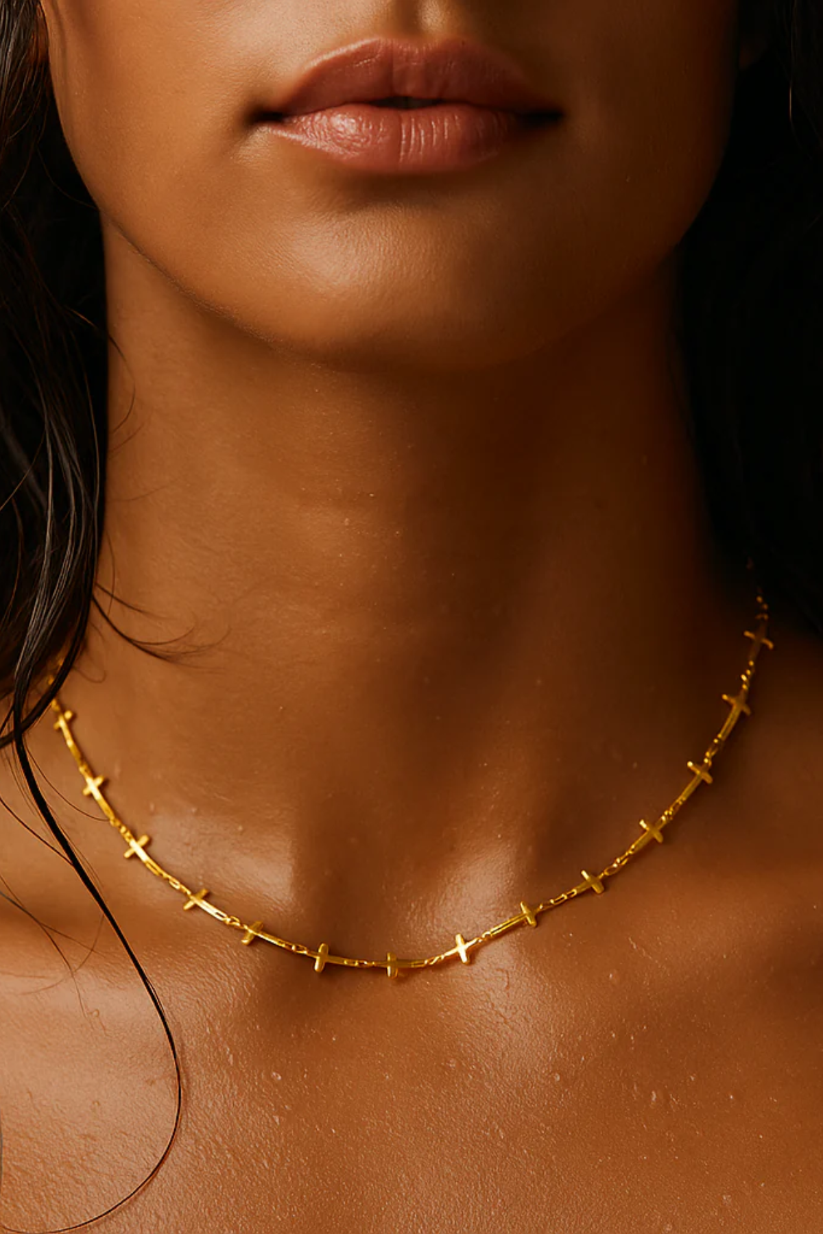 Close-up of a person wearing a gold necklace with a blurred background