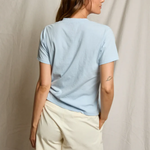 Woman wearing a light blue t-shirt and beige shorts against a neutral background