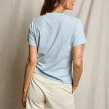 Woman wearing a light blue t-shirt and beige shorts against a neutral background