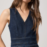 Woman wearing a blue denim dress against a plain background