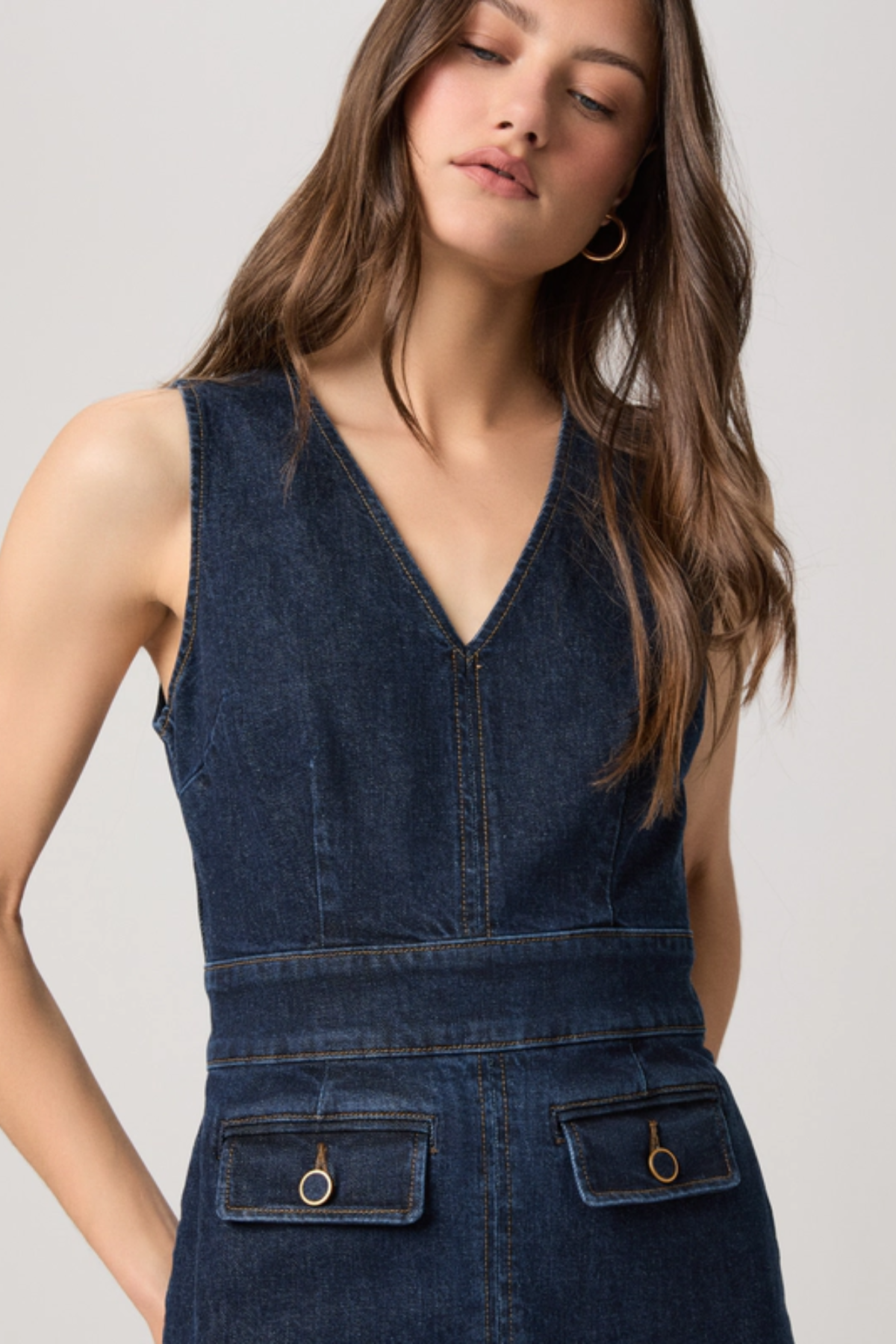 Woman wearing a blue denim dress against a plain background