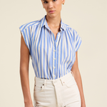 Woman wearing a blue and white striped shirt with white pants on a beige background