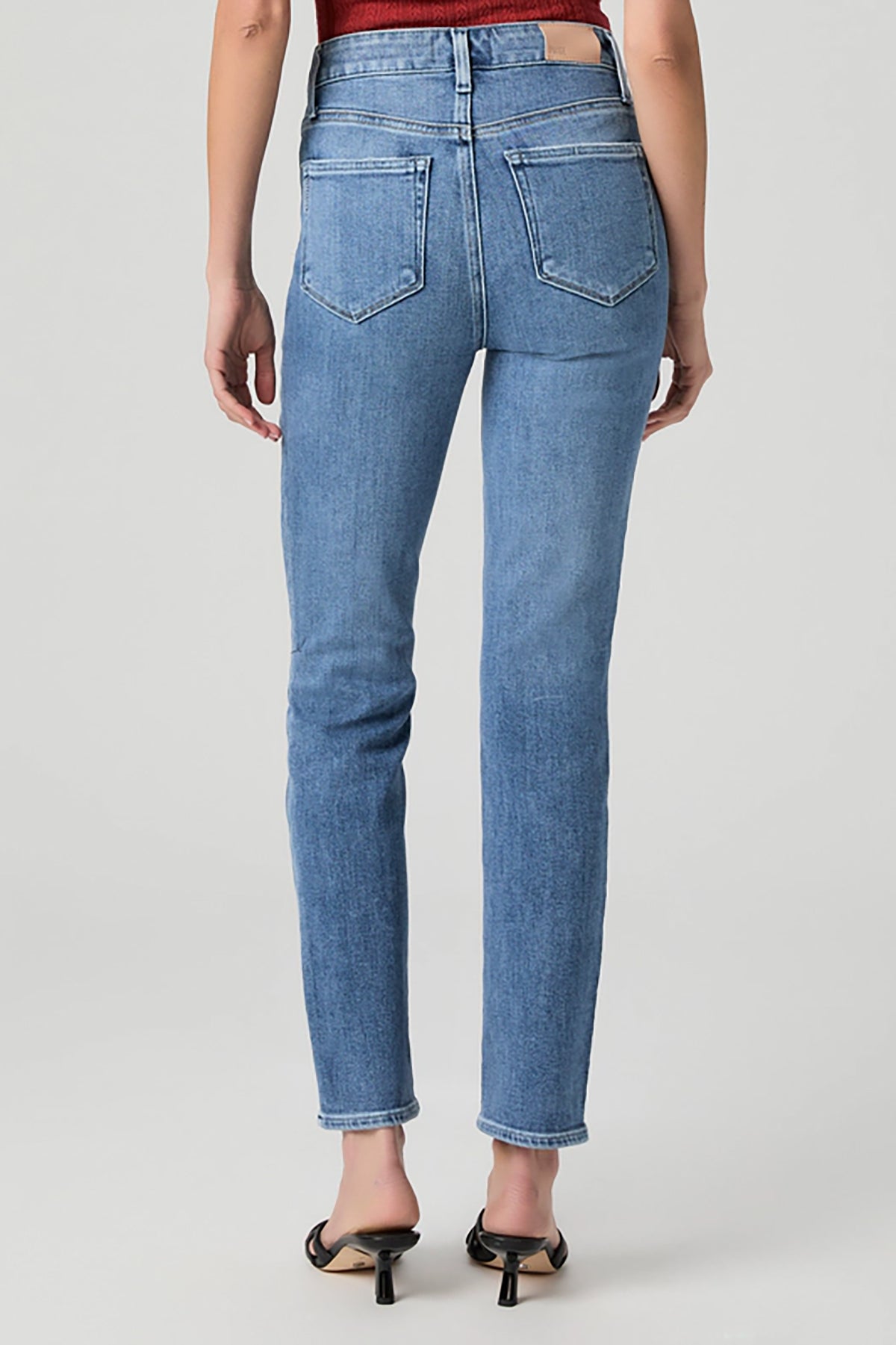Woman wearing mid-wash straight-leg jeans with a streamlined, classic silhouette.