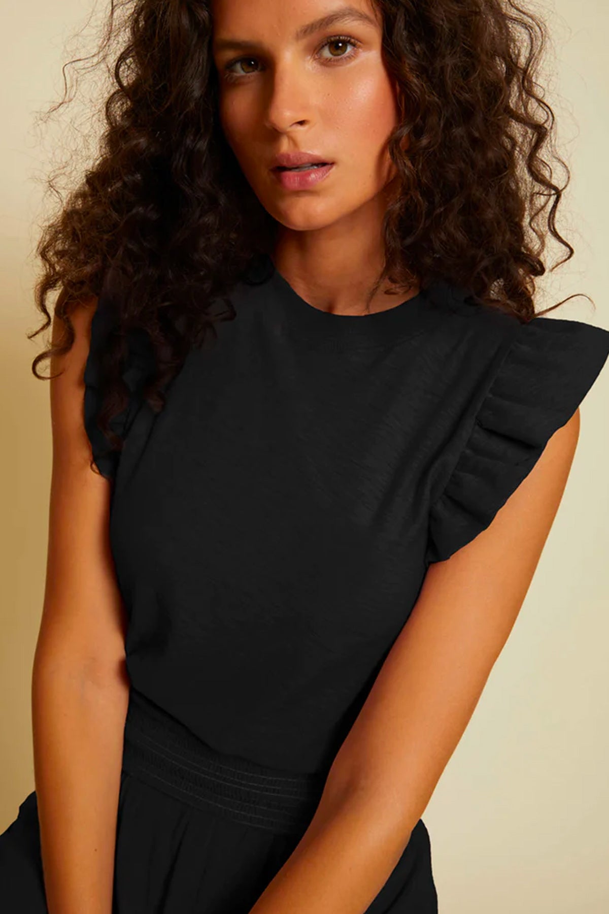 woman black ruffle sleeve top on beige background 